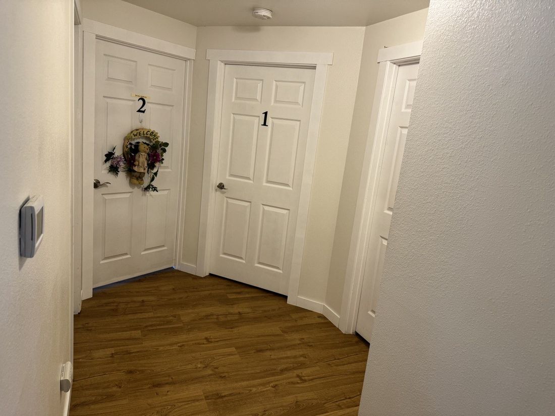 A welcoming hallway of private resident rooms, each personalized at the door