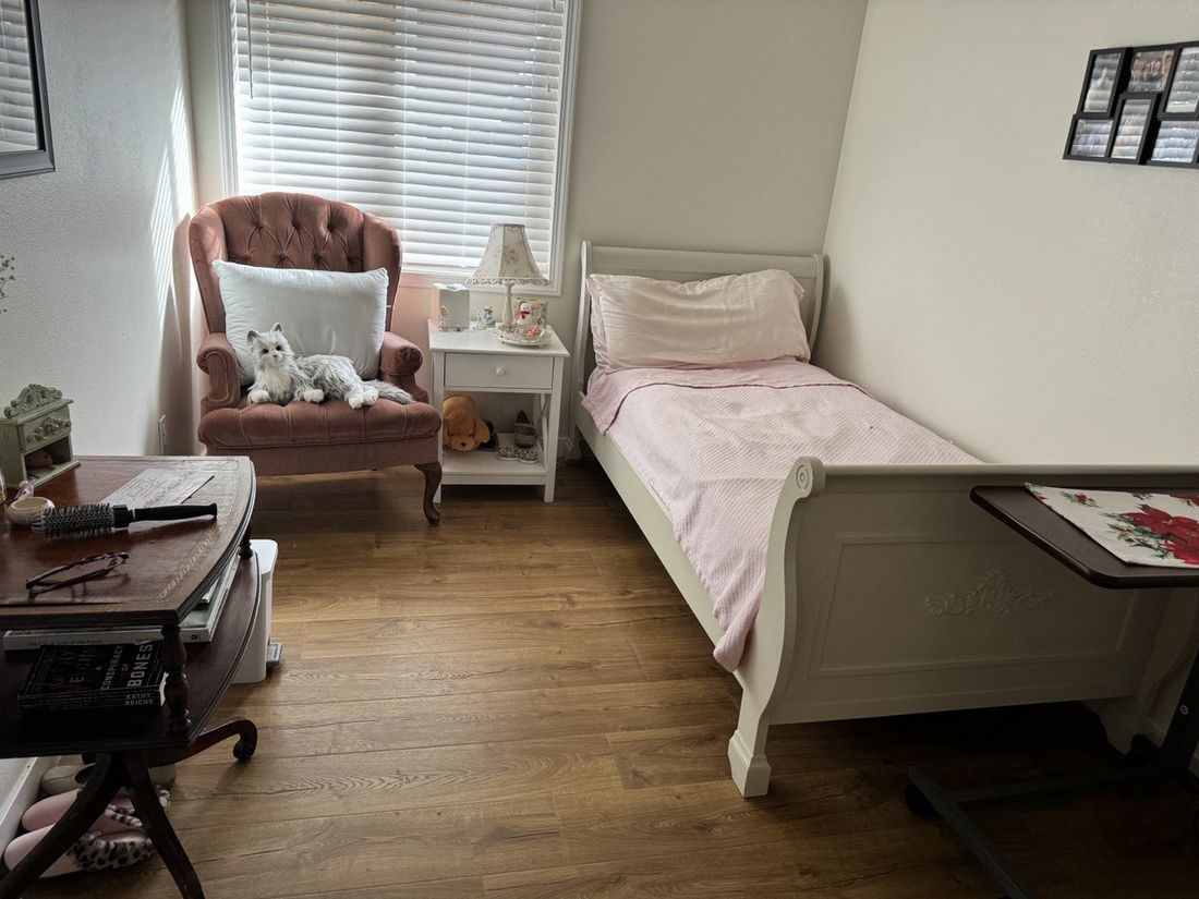 A bright, cozy private resident bedroom with a comfortable armchair by the sunny window